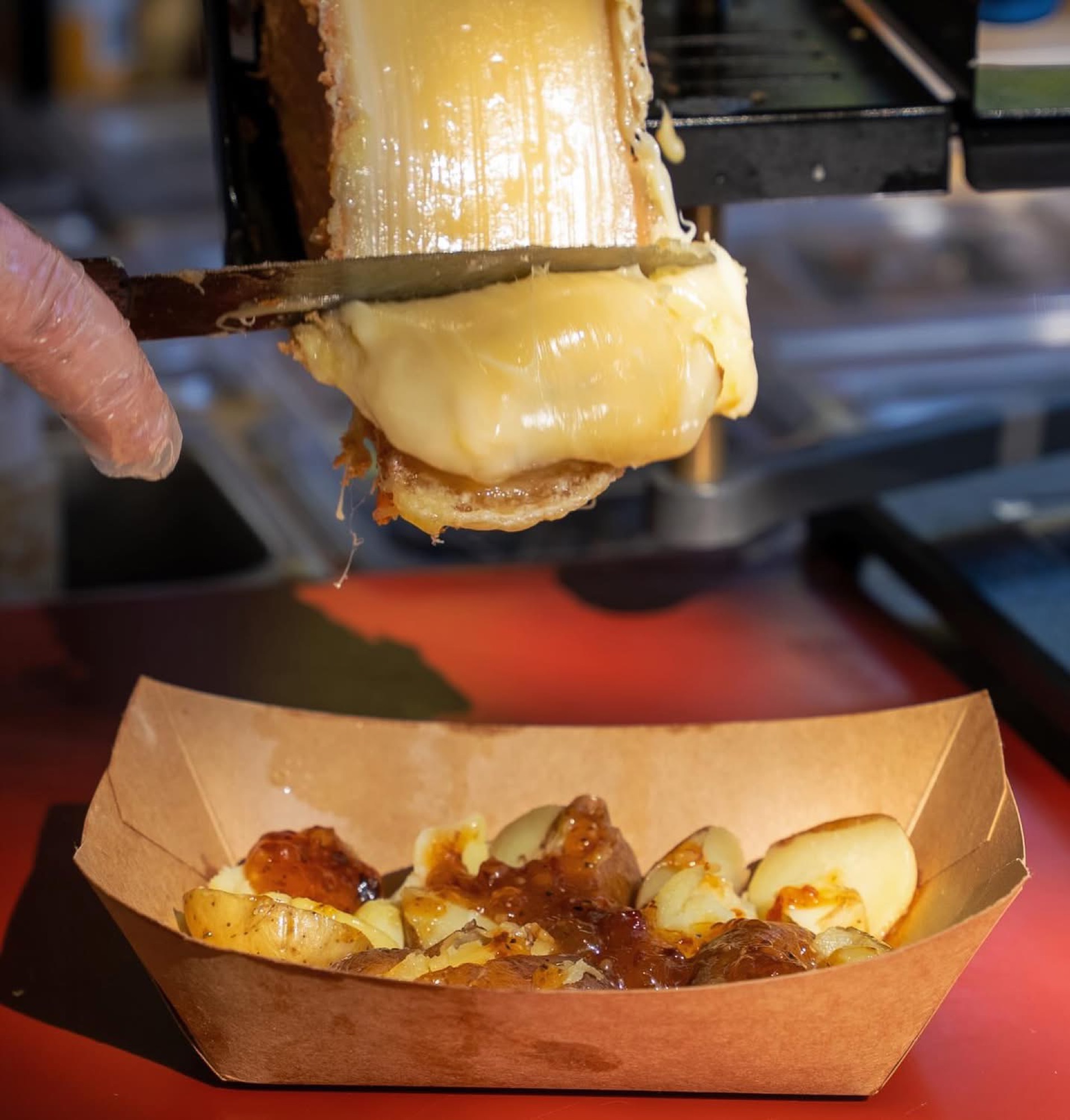 Raclette cheese scraped fresh over loaded potatoes at a Melted State event